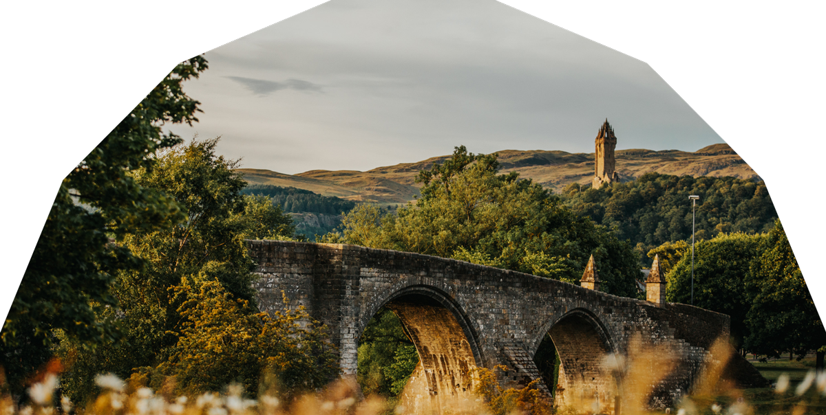 A bridge against a backdrop of Scottish hills and the Wallace Monument tower