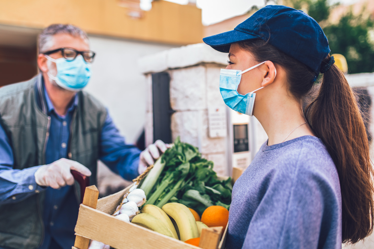 A girl hands over a crate of vegetables to a man