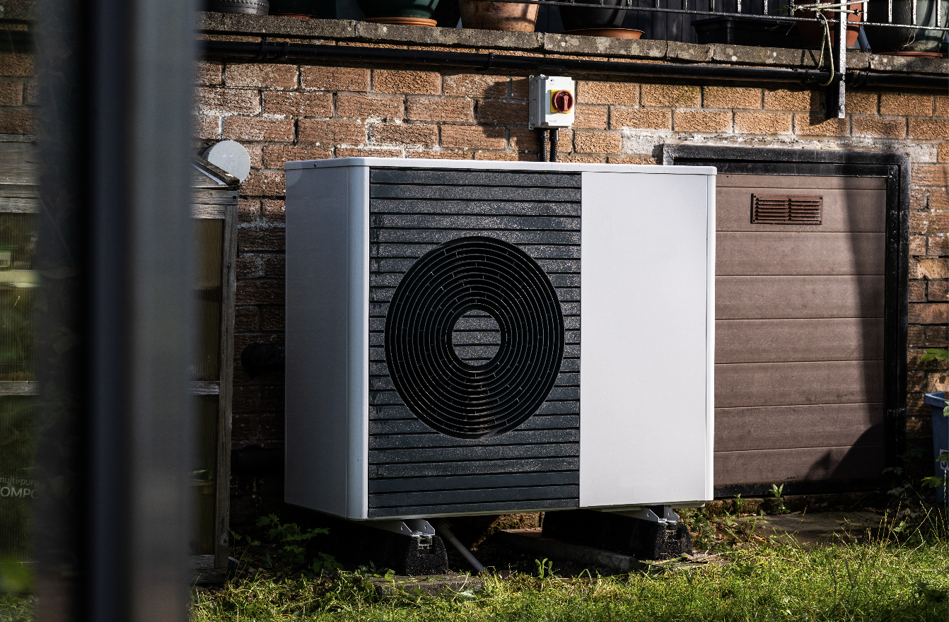 heat pump outside of a brick building with grass in front