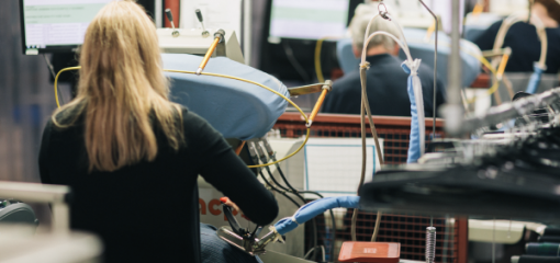 A machinist with long blonde hair works in a textile factory.