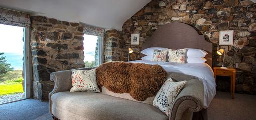 A bedroom with a sheepskin rug over a sofa at the foot of a bed