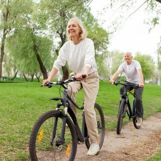 Two people cycling their bikes through a woodland area