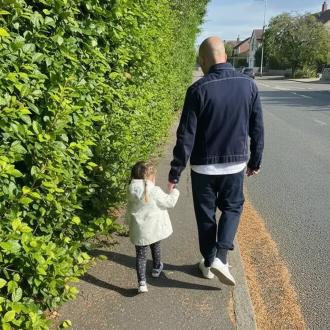 man walking with daughter on the pavement, holding hands