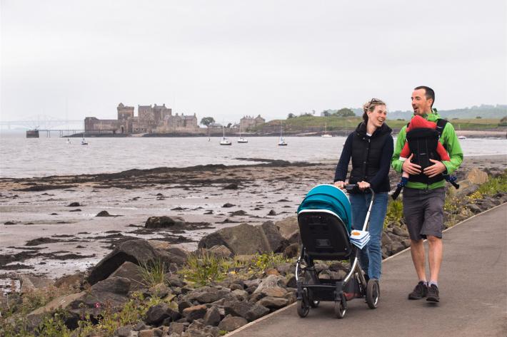 A couple walking by the sea with a pram