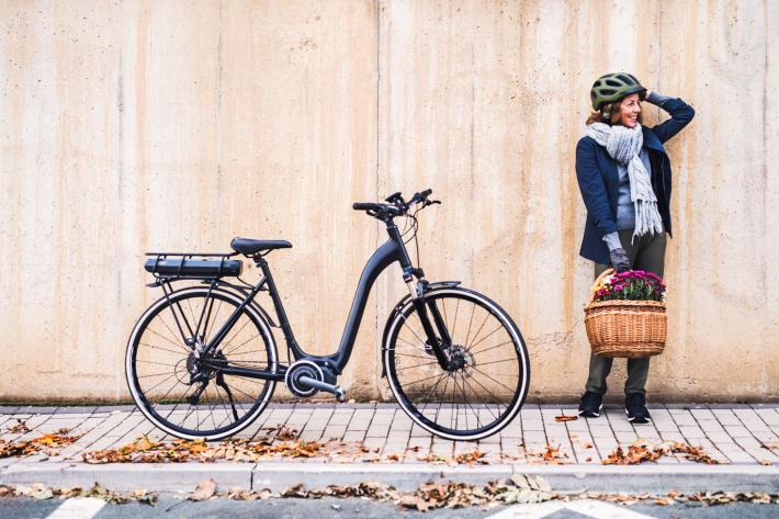 A person holding a basket next to a bicycle