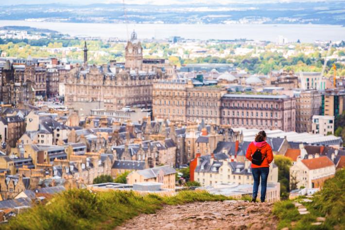 A person walking on a hill with a city view in the background