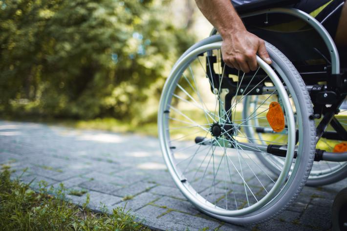 A man's hand holding onto the wheel of a wheelchair