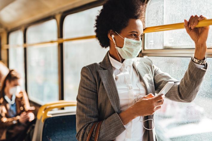 A woman on a bus wearing a face mask