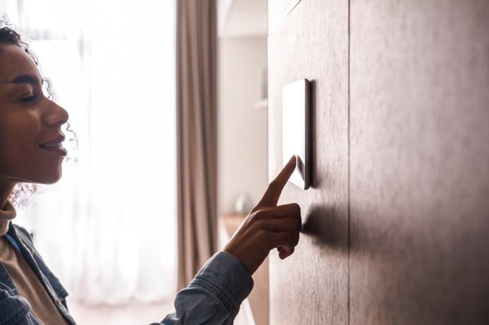 A woman pressing a home energy thermostat