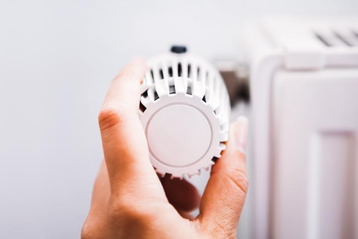 A hand turning the temperature guage on a radiator