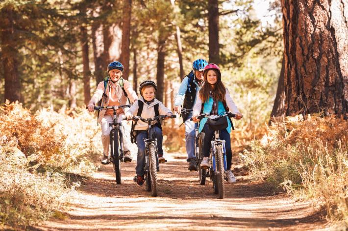 Two adults and two kids cycling through a forest