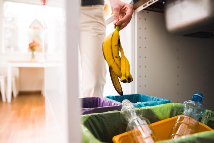 A person putting a banana peel in their food recycling bin.