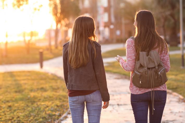 Two girls walking through a park