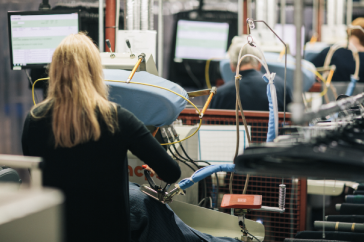 A machinist with long blonde hair works in a textile factory.