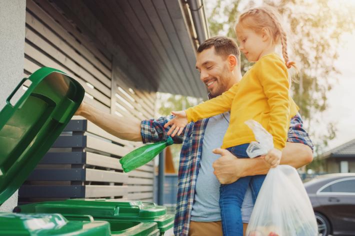 Young dad showing daughter how to recycle