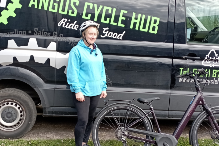 Woman standing in front of a van with a bike