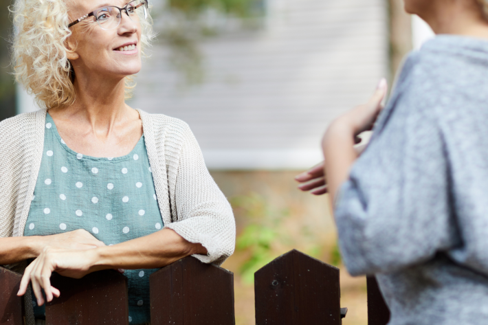 Two women talking to each other over a fence