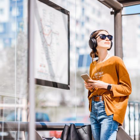 A girl in an orange jumper standing in a bus stop.