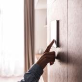 A woman pressing a home energy thermostat