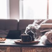 A pot of tea and cup on a small table in a living room