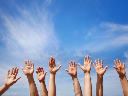 hands in the air in front of a blue sky