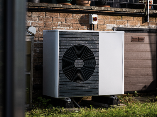 heat pump outside of a brick building with grass in front