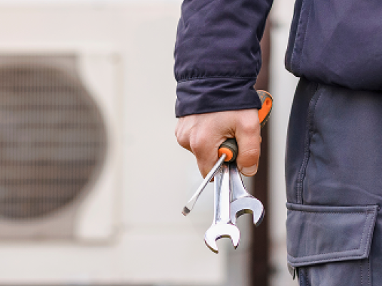 close up photograph of a person's hand holding a screwdriver and two wrenches